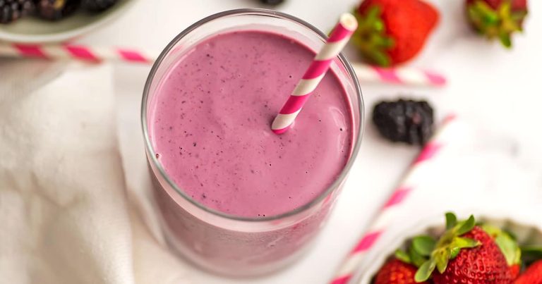 Blackberry strawberry banana smoothie in a glass with a straw.