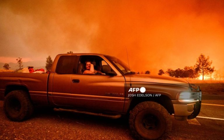 Surrounded by flames, resident Andrea Douglas waits on the side of the road while evacuating with her husband Grant as the Park fire continues to burn near Paynes Creek in unincorporated Tehama County, California on July 26, 2024.