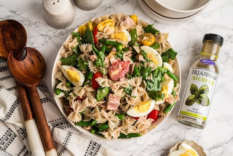 Ni&ccedil;oise tuna pasta salad in a white bowl, wood spoons on the side.